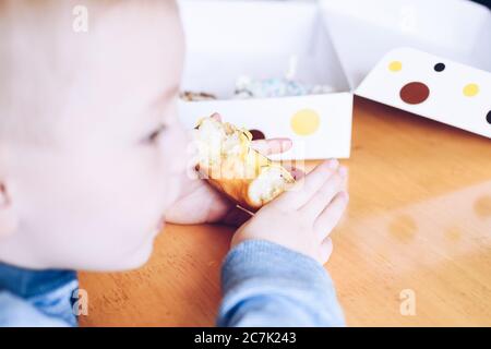 Petit garçon mange banane jaune beigne givré. La nourriture bonne pour les enfants. Family eating donuts à partir de la livraison de nourriture. Mode de vie malsain concept. Banque D'Images