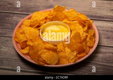 Croustilles sur un plateau rond et une casserole avec sauce au fromage. Gros plan Banque D'Images