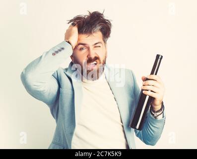 Élégant homme beau en costume bleu buvant à la bouteille sur fond blanc. Banque D'Images