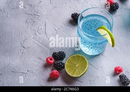 Délicieux cocktail de couleur bleue avec graines de basilic chia, tranche de citron vert, framboise et mûres de mûre en verre, boisson d'été saine Banque D'Images