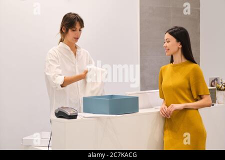 Jeune conseiller en mode attrayant emballage robe dans boîte au client en magasin Banque D'Images