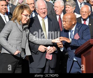 L’ancienne Représentante américaine Gabrielle Giffords (démocrate de l’Arizona), à gauche, est accueillie par le Représentant américain John Lewis (démocrate de la Géorgie), à droite, Alors qu'elle arrive à la Chambre des représentants démocrates américains lorsqu'ils apparaissent sur les marches est du Capitole des États-Unis pour faire une déclaration contre la violence par les armes à feu dans le sillage du massacre de Las Vegas à Washington, DC, le mercredi 4 octobre 2017. Le représentant américain Mike Thompson (démocrate de Californie) est à l'affût du centre. Crédit : Ron Sachs/CNP | utilisation dans le monde entier Banque D'Images