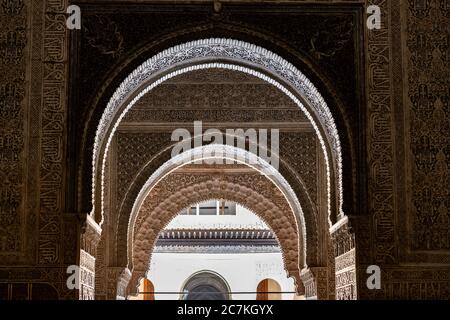 La lumière capture les bords d'un arabesque des arches en fer à cheval très ouvragées qui mènent de la salle des deux sœurs de l'Alhambra à la cour des Lions Banque D'Images