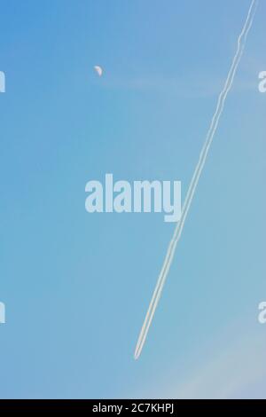 Photo verticale du ciel bleu magnifique avec moteur d'avion sentiers et la demi-lune Banque D'Images