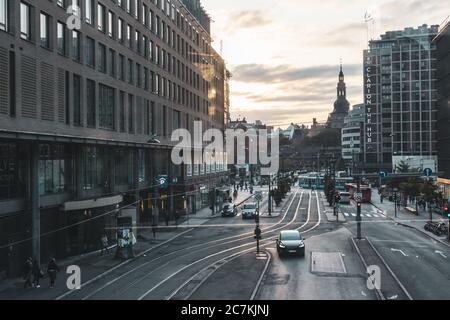 Oslo, Norvège - 10 septembre 2019 : paysage du centre-ville avec chemin de fer, bâtiments modernes et anciens, carrefour en lumière du coucher de soleil chaude avec nuage dramatique Banque D'Images