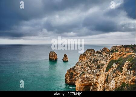 Europe, Portugal, Algarve, Litoral, Barlavento, Felsalgarve, Faro District, Lagos, côte de la Ponta da Piedade, avec récif rocheux au large, couvert de nuages Banque D'Images