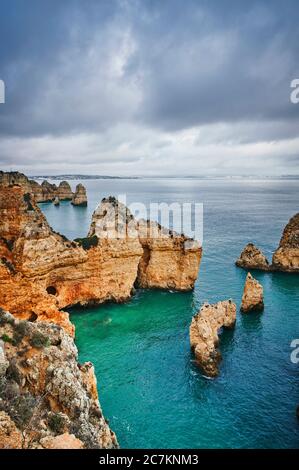 Europe, Portugal, Algarve, Litoral, Barlavento, Felsalgarve, district de Faro, Lagos, Ponta da Piedade, lagune avec récif et vue lointaine, formations de nuages, format portrait Banque D'Images