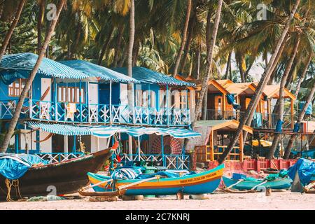 Canacona, Goa, Inde. Bateau de pêche et célèbres maisons d'hôtes peintes sur la plage de Palolem sur fond de grands palmiers en Sunny Day. Banque D'Images