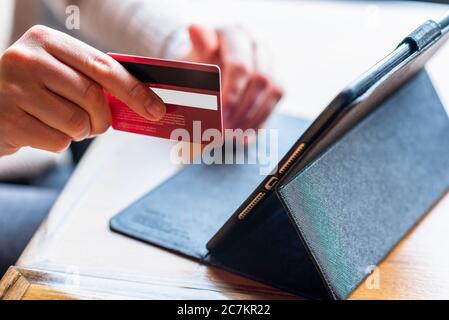 Gros plan mains de femme tenant une carte de crédit et utilisant une tablette pour les achats en ligne, e-banking. Banque D'Images