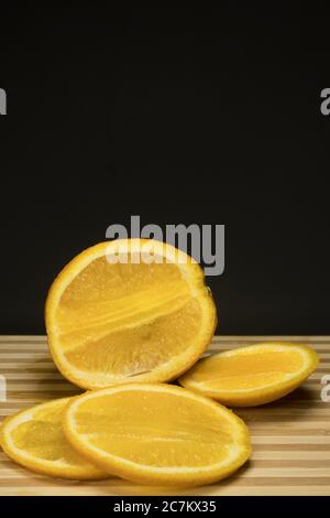 Morceaux d'orange frais sur plateau en bois avec noir Banque D'Images