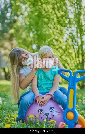 Mère met sur masque de visage, fille, terrain de jeu, crise corona, Regensburg, Bavière, Allemagne Banque D'Images