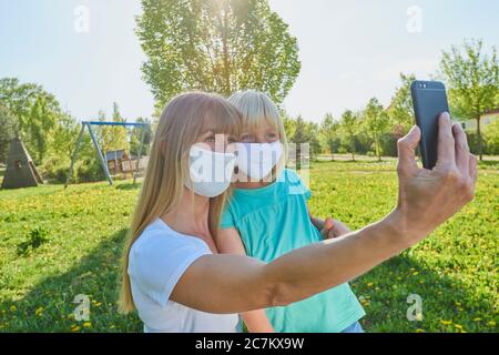 Mère et fille avec masque de visage font selfie dans un parc de ville, crise de Corona, Ratisbonne, Bavière, Allemagne Banque D'Images