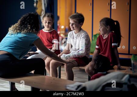 Jeune femme entraîneur prenant soin de garçon de sport après accident physique. Banque D'Images