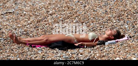 Une femme profite du soleil et du temps chaud sur Brighton Beach. Banque D'Images