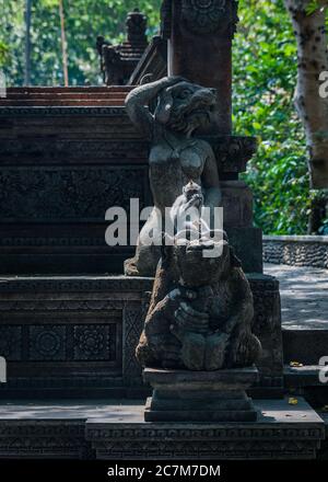 Gros plan d'un singe assis sur une vieille sculpture dans un parc par jour ensoleillé Banque D'Images