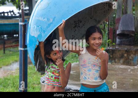 Deux petites filles adorables trouvent un abri sous un pavillon de téléphone depuis une douche à effet pluie dans la ville de Curua una, dans l'État de Para, au Brésil. Banque D'Images