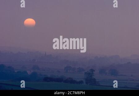 Coucher de soleil de Moody au-dessus du village d'Ingleton, dans les Yorkshire Dales en regardant vers la flèche de l'église All Saints dans le village voisin de Burton à Lonsdale vers 1990 Banque D'Images