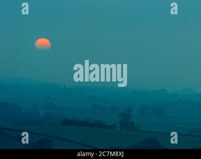 Coucher de soleil de Moody au-dessus du village d'Ingleton, dans les Yorkshire Dales en regardant vers la flèche de l'église All Saints dans le village voisin de Burton à Lonsdale vers 1990 Banque D'Images