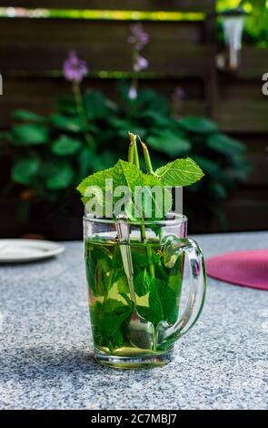 Un verre de thé à la menthe sur une table en marbre à l'extérieur du jardin. Banque D'Images