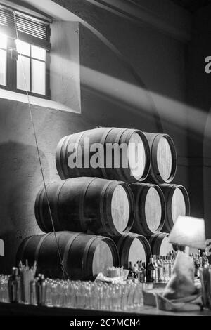 Prise de vue en niveaux de gris d'un tas de barils en bois avec du verre flacons sur la surface Banque D'Images