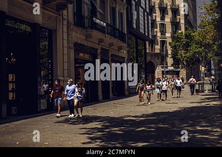 Barcelone, Espagne. 18 juillet 2020. Les voyageurs portant un masque facial protecteur descendent un Passeig de Gracia exceptionnellement vide alors que le gouvernement catalan a exhorté les habitants de la zone métropolitaine de Barcelone à rester chez eux face à l'augmentation quotidienne la plus abrupte des nouveaux cas de COVID-19 après avoir émergé des mesures de verrouillage nationales il y a moins d'un mois. Crédit: Matthias Oesterle/Alamy Live News Banque D'Images