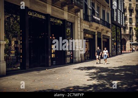 Barcelone, Espagne. 18 juillet 2020. Les voyageurs portant un masque facial protecteur descendent un Passeig de Gracia exceptionnellement vide alors que le gouvernement catalan a exhorté les habitants de la zone métropolitaine de Barcelone à rester chez eux face à l'augmentation quotidienne la plus abrupte des nouveaux cas de COVID-19 après avoir émergé des mesures de verrouillage nationales il y a moins d'un mois. Crédit: Matthias Oesterle/Alamy Live News Banque D'Images