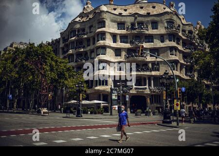 Barcelone, Espagne. 18 juillet 2020. Un travailleur de voyage portant un masque facial protecteur passe devant la Pedrera de Gaudi, alors que le gouvernement catalan a exhorté les habitants de la région métropolitaine de Barcelone à rester chez eux face à l'augmentation quotidienne la plus abrupte des nouveaux cas de COVID-19 après avoir émergé des mesures de confinement à l'échelle nationale il y a moins d'un mois. Crédit: Matthias Oesterle/Alamy Live News Banque D'Images