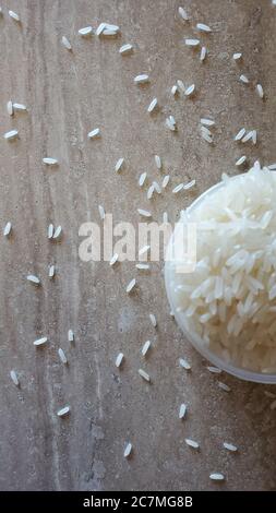 Concentrez-vous sur l'arrière-plan et le premier plan défoqué avec une tasse graduée pleine de riz. Vue de dessus des grains de riz mess éparpillés sur la surface en marbre du plan d'examen Banque D'Images