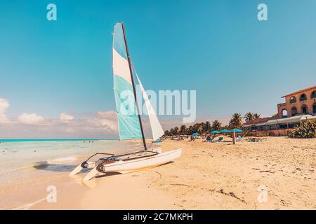 Catamaran blanc bleu voile sur la plage de sable blanc avec effet rétro. plage de Varadero à Cuba Banque D'Images