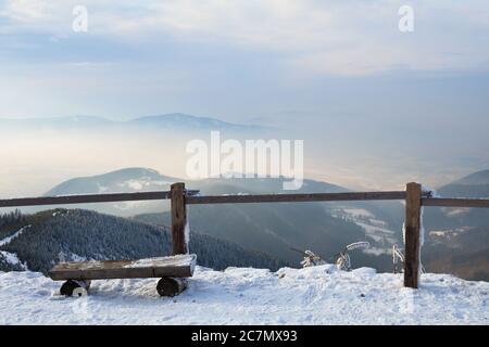 Beskids montagnes ( Beskydy ), République Tchèque / Tchéquie - vue depuis le sommet de la colline. Banc en bois pour s'asseoir et rambarde en bois. Neige en hiver. Pour Banque D'Images