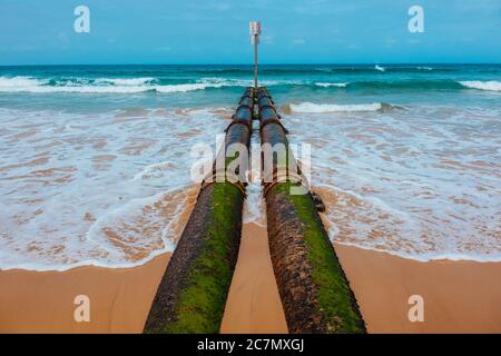 Deux tuyaux de couleur rouille et verte sur la plage capturés une journée ensoleillée Banque D'Images