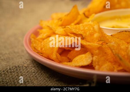 Croustilles sur un plateau rond et une casserole avec sauce au fromage. Gros plan Banque D'Images