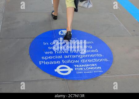 Londres, Royaume-Uni. 18 juillet 2020. Une femme marche sur un panneau sur le London Bridge pour rappeler aux gens les règles de distanciation sociale. Le centre de Londres semblait aujourd'hui plus occupé avec plus de personnes qui quittait leur maison pour profiter du temps ensoleillé. Les règles de distanciation sociale semblaient être respectées dans la plupart des endroits, mais certaines zones sont déjà bondées. Crédit : Imagetraceur/Alamy Live News Banque D'Images