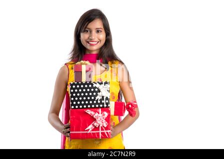 Portrait de jeune fille indienne souriante et heureuse tenant des boîtes-cadeaux sur un fond blanc. Banque D'Images