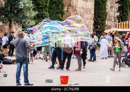 Un Espagnol d'âge moyen fait des bulles géantes pour divertir les touristes en face de la cathédrale de Barcelone, Barcelone, Espagne. Banque D'Images