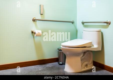 Moderne accessible aux personnes handicapées salle de bains propre avec toilettes modernes japonaises toilettes mur de couleur verte et sol en béton avec papier hygiénique Banque D'Images