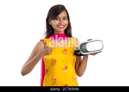 Jeune fille traditionnelle indienne tenant et montrant un appareil VR, boîte vr, lunettes, casque de réalité virtuelle 3D, fille avec l'imagerie moderne future technologie Banque D'Images