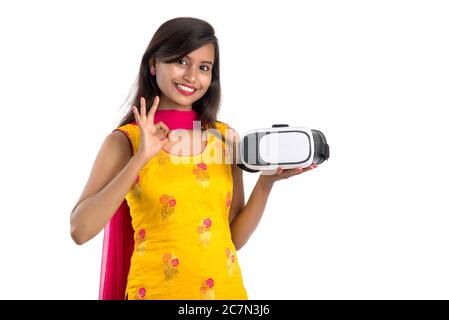 Jeune fille traditionnelle indienne tenant et montrant un appareil VR, boîte vr, lunettes, casque de réalité virtuelle 3D, fille avec l'imagerie moderne future technologie Banque D'Images