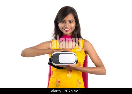 Jeune fille traditionnelle indienne tenant et montrant un appareil VR, boîte vr, lunettes, casque de réalité virtuelle 3D, fille avec l'imagerie moderne future technologie Banque D'Images