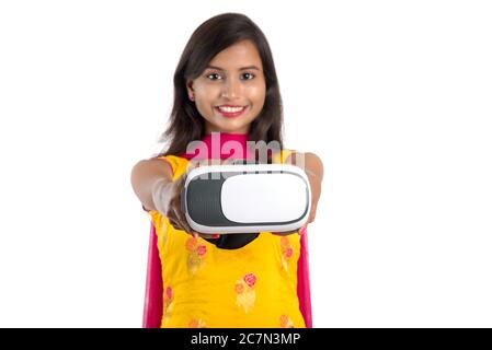 Jeune fille traditionnelle indienne tenant et montrant un appareil VR, boîte vr, lunettes, casque de réalité virtuelle 3D, fille avec l'imagerie moderne future technologie Banque D'Images