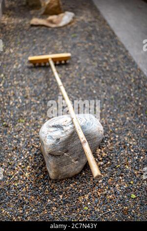 Petit jardin de roche zen en plein air dans le temple du Japon avec rake à proximité sur pierre et motif sur fond de gravier et personne par chemin Banque D'Images