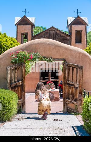 Chimayo, USA - 19 juin 2019: El Santuario de Chimayo sanctuaire église aux Etats-Unis avec porte d'entrée et femme priant pour le miracle Banque D'Images