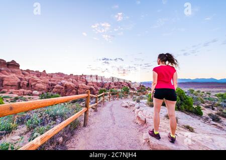 Vue grand angle avec une jeune fille derrière le sentier de randonnée le matin du lever du soleil dans le parc national d'Arches, Utah, États-Unis au point de vue Fiery Furnace avec landsca Banque D'Images