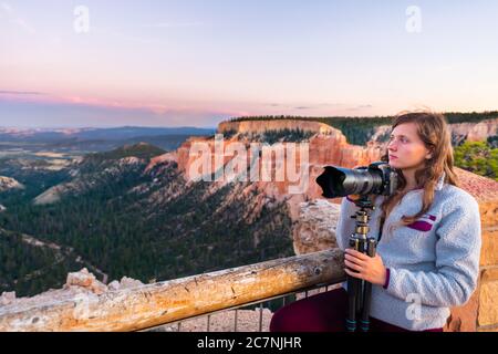 Femme prenant des photos de la vue de Paria vue sur les formations rocheuses de Hoodoos dans le parc national de Bryce Canyon au coucher du soleil avec trépied et appareil photo Banque D'Images