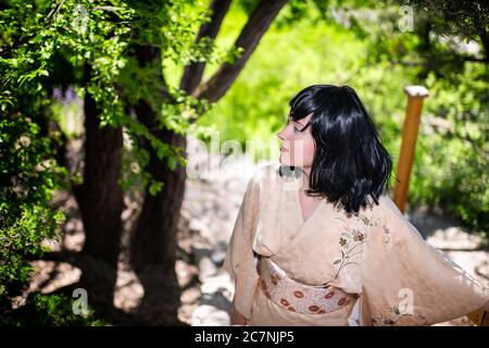 Jeune femme en costume kimono sur marches escalier avec barrière en bois dans jardin extérieur dans le Japon nature arrière-plan Banque D'Images