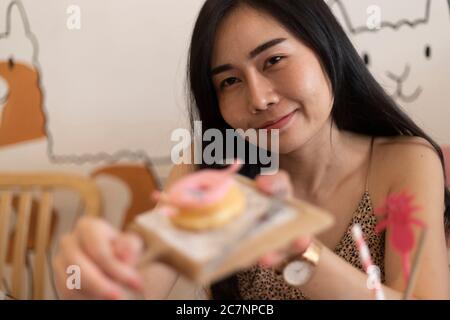 Jeune fille mangeant un beignet à la cafétéria. Banque D'Images