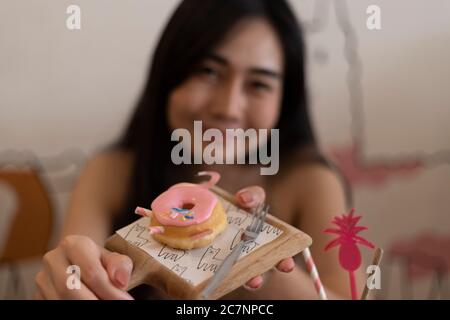 Jeune fille mangeant un beignet à la cafétéria. Banque D'Images