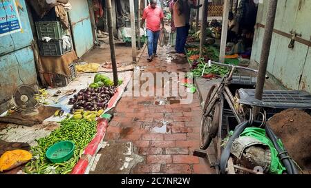 Ruelle étroite à l'intérieur d'un marché de la ville avec des vendeurs vendant Légumes et clients dans un bazar à Kolkata Inde Banque D'Images