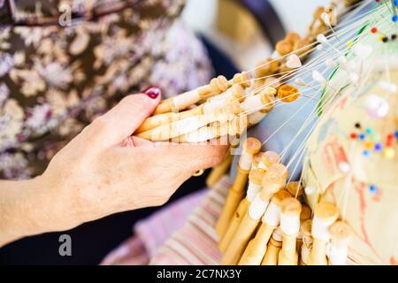 Gros plan d'une main de femme tenant un tas de outils traditionnels de laçage de la bobine Banque D'Images