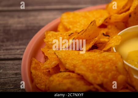 Croustilles sur un plateau rond et une casserole avec sauce au fromage. Gros plan Banque D'Images